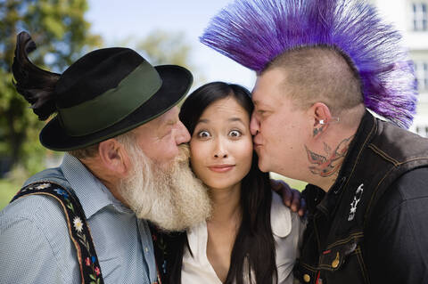 Germany, Bavaria, Upper Bavaria, Two men kissing Asian woman on cheek, portrait stock photo