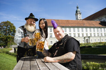 Deutschland, Bayern, Oberbayern, Drei Personen im Biergarten mit Bierkrügen in der Hand, lächelnd - WESTF09548