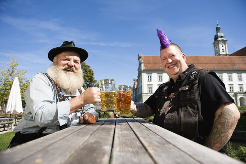 Germany, Bavaria, Upper Bavaria, Man with mohawk hairstyle and Bavarian man in beer garden - WESTF09543