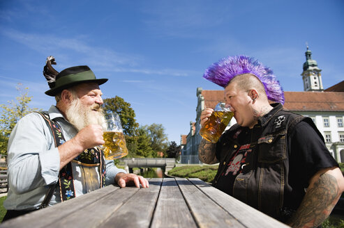 Germany, Bavaria, Upper Bavaria, Man with mohawk hairstyle and Bavarian man in beer garden - WESTF09542