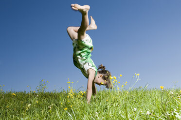 Young girl (6-7) in the meadow doing a handstand - CLF00616