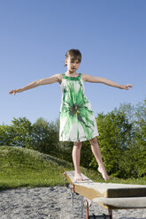 Junges Mädchen (7 Jahre) balanciert auf der Promenade eines Spielplatzes - CLF00612