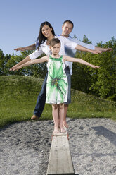 Junge Familie balanciert auf der Promenade eines Spielplatzes - CLF00610