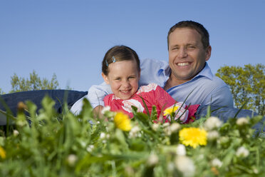 Vater und Tochter (6-7) entspannen sich auf der Wiese, lächelnd - CLF00578