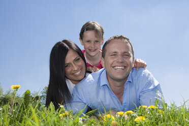 Junge Familie mit Tochter (6-7) auf der Wiese liegend, lächelnd, Porträt - CLF00573