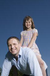 Kleines Mädchen (6-7) auf dem Rücken des Vaters sitzend, lächelnd - CLF00568