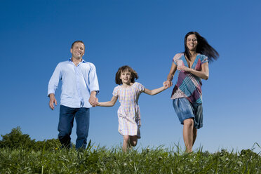 Junge Familie mit Tochter (6-7) bei einem Spaziergang über eine Wiese - CLF00561