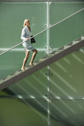 Germany, businesswoman climbing stairs, smiling - WESTF10236