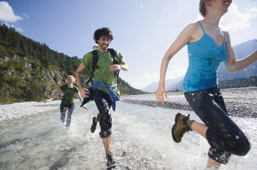 Deutschland, Bayern, Tölzer Land, Junge Leute laufen durch Fluss - WESTF09917