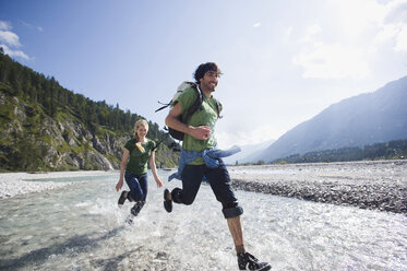 Germany, Bavaria, Tölzer Land, Young couple running through river - WESTF09915