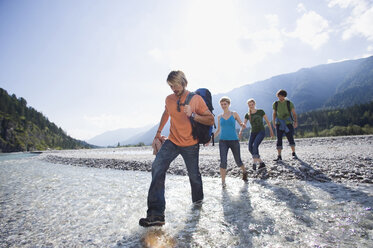 Germany, Bavaria, Tölzer Land, Young friends walking through river - WESTF09910