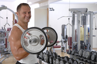 Man lifting a Dumbbell, smiling, portrait - ASF03796