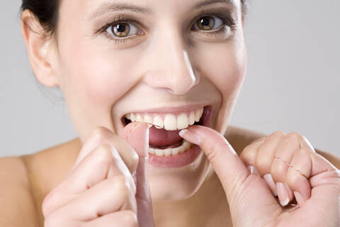 Junge Frau bei der Verwendung von Zahnseide, Nahaufnahme, lizenzfreies Stockfoto