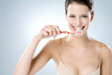 Junge Frau putzt sich die Zähne, lächelnd, Nahaufnahme - MAEF01287