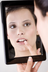 Junge Frau betrachtet ihr Spiegelbild, Nahaufnahme - MAEF01271