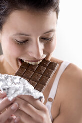 Young woman biting into chocolate bar, close up - MAEF01265