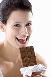 Young woman holding chocolate bar, smiling - MAEF01264