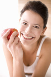 Junge Frau hält einen Apfel und lächelt - MAEF01230