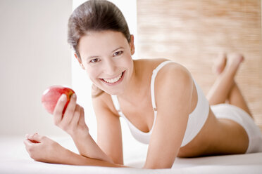 Junge Frau hält einen Apfel und lächelt - MAEF01229