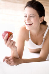 Junge Frau hält einen Apfel und lächelt - MAEF01228