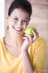 Young woman holding an apple, smiling, portrait - MAEF01211