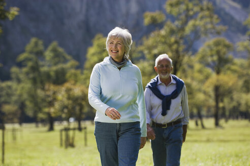 Austria, Karwendel, Senior couple walking across meadow - WESTF10542