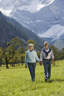 Austria, Ahornboden, Senior couple walking across meadow, hand in hand - WESTF10539