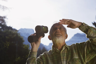 Austria, Karwendel, Senior man holding binocular, looking up - WESTF10501