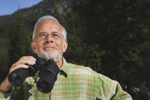 Austria, Karwendel, Senior man holding binocular, portrait stock photo