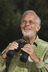 Austria, Karwendel, Senior man holding binocular, portrait - WESTF10498