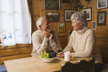 Senior couple sitting at table, smiling - WESTF10416