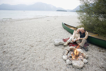 Germany, Bavaria, Senior couple sitting at campfire - WESTF10224