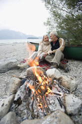 Germany, Bavaria, Senior couple sitting at campfire - WESTF10223