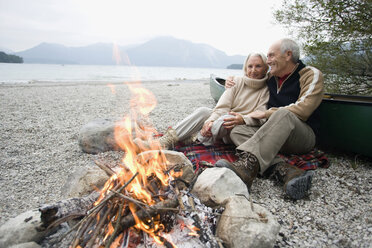 Germany, Bavaria, Senior couple sitting at campfire - WESTF10222
