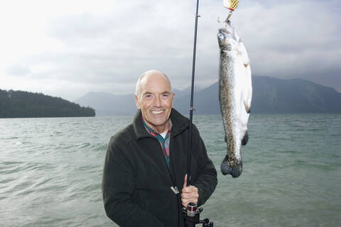 Germany, Bavaria, Walchensee, Senior man fishing in lake stock photo
