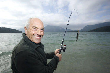 Happy senior man holding fish on fishing line stock photo