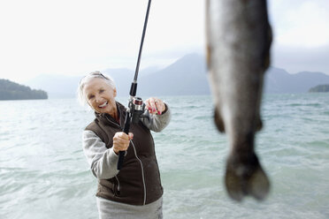 Germany, Bavaria, Walchsensee, Senior woman fishing in lake - WESTF10201