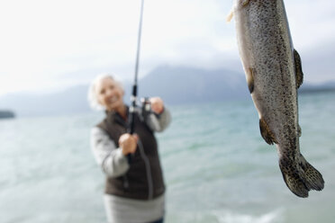 Germany, Bavaria, Walchsensee, Senior woman fishing in lake - WESTF10200