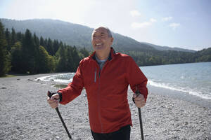 Deutschland, Bayern, Walchensee, Senior Mann mit Nordic Walking Stöcken, lächelnd - WESTF10181