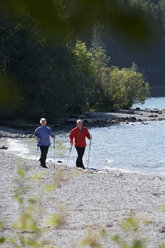 Germany, Bavaria, Walchensee, Senior couple, Nordic Walking on lakeshore - WESTF10175