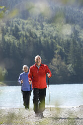 Germany, Bavaria, Walchensee, Senior couple, Nordic Walking on lakeshore - WESTF10173