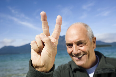 Germany, Bavaria, Walchensee, Senior man showing victory sign - WESTF10168