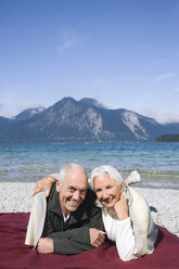 Germany, Bavaria, Walchensee, Senior couple relaxing on lakeshore - WESTF10147