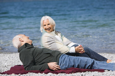 Germany, Bavaria, Walchensee, Senior couple relaxing on lakeshore - WESTF10139