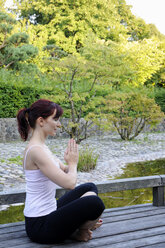 Deutschland, Bayern, München, Junge Frau übt Yoga, Hände gefaltet - NHF00973