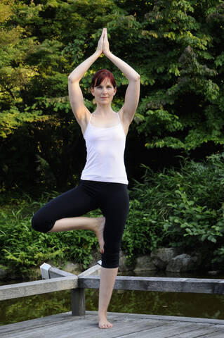 Deutschland, Bayern, München, Junge Frau übt Yoga, Hände über Kopf, lizenzfreies Stockfoto