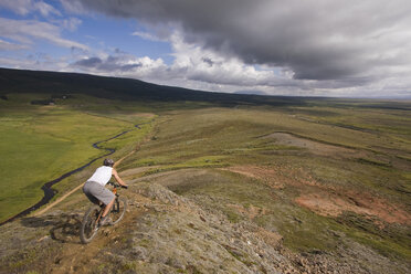 Iceland, Man mountain biking across hilly landscape - FFF00955