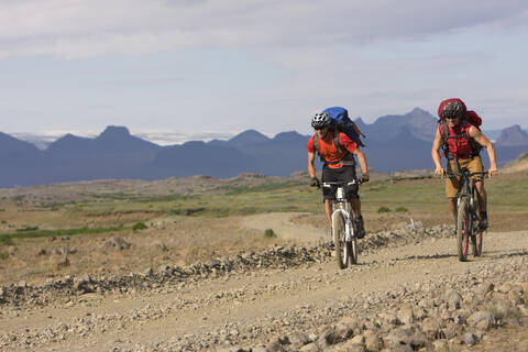 Island, Männer beim Mountainbiking in hügeliger Landschaft, lizenzfreies Stockfoto