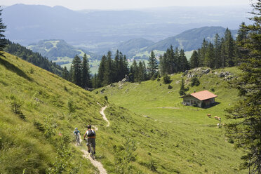 Deutschland, Bayern, Chiemgau, Zwei Männer fahren mit dem Mountainbike durch eine Berglandschaft - FFF00944