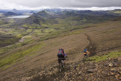 Island, Männer beim Mountainbiking in hügeliger Landschaft, lizenzfreies Stockfoto